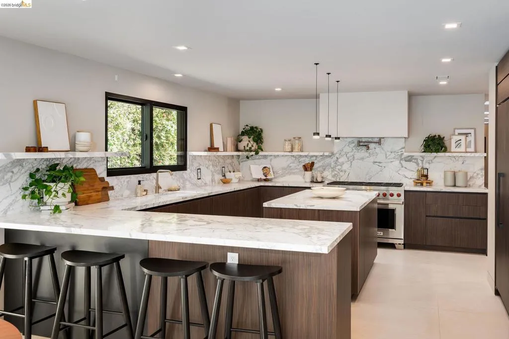 Modern kitchen featuring dark wood-finish cabinetry, white stone countertops, and a full-height stone backsplash