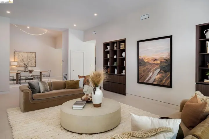 Spacious living area featuring light-toned walls, recessed lighting, and built-in dark wood shelving units