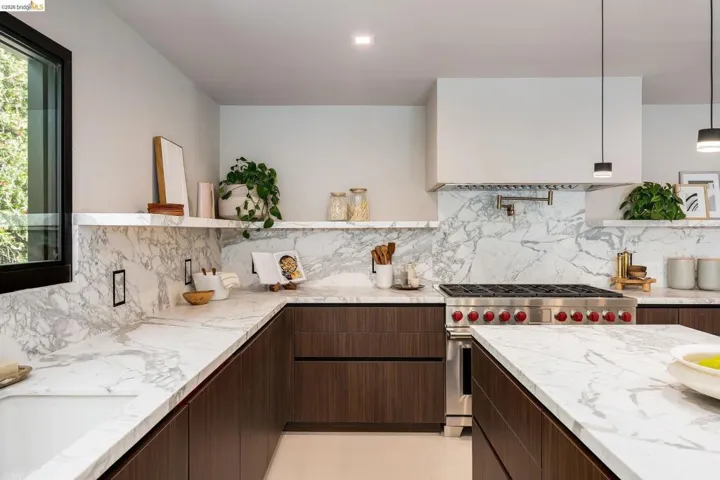 Gourmet kitchen featuring a built-in stainless steel range, marble countertops and backsplash, dark wood-finish cabinetry, and recessed lighting