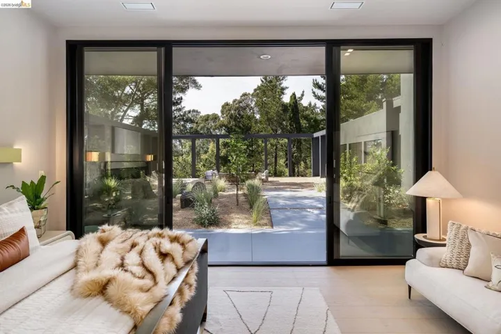 Floor-to-ceiling glass doors opening to a landscaped outdoor space