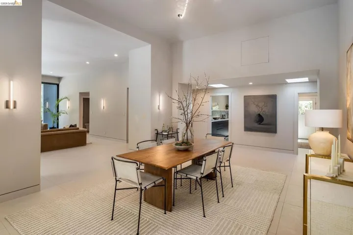 Open-concept interior featuring light-toned flooring, high ceilings, recessed lighting, and wall-mounted sconces
