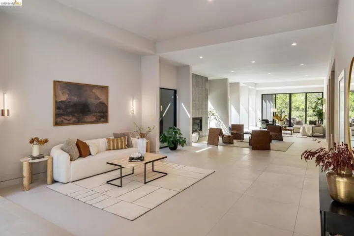 Spacious main living area featuring light-toned tile flooring, recessed lighting, and wall sconces