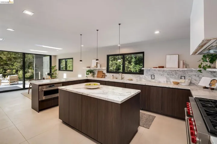 Modern kitchen featuring dual islands with stone countertops, dark wood-finish cabinetry, and a full-height stone backsplash