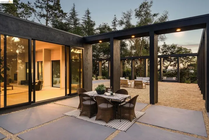 Expansive outdoor living area featuring a large patio with concrete pavers, an open-air pergola structure, and a gravel-covered gathering space