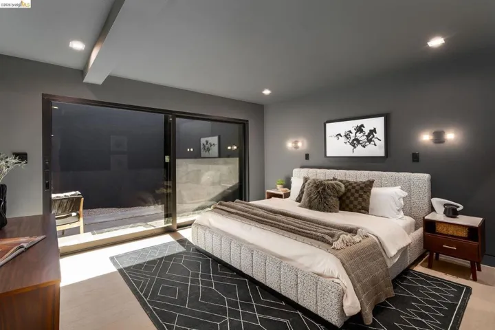 Bedroom featuring a sliding glass door, recessed lighting, wall sconces, light wood-finish flooring, and a dark accent wall