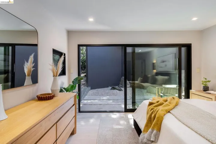 Bedroom featuring light wood-finish flooring, recessed lighting, and a large sliding glass door opening to an outdoor patio area with gravel and plantings