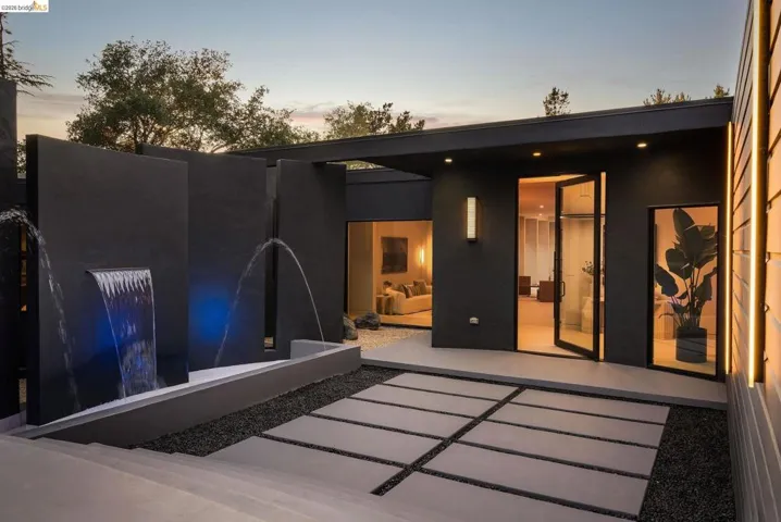 Modern exterior featuring a prominent water feature with blue accent lighting