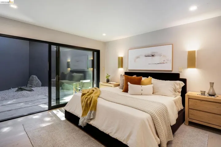 Light-toned flooring in a bedroom featuring a sliding glass door opening to a private outdoor space with gravel and stone elements