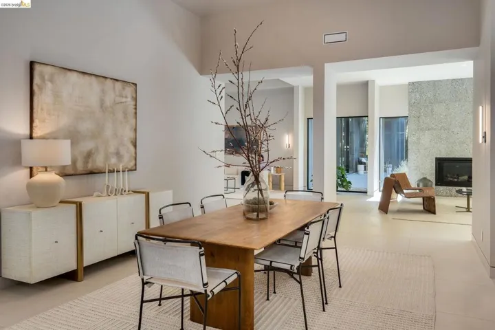 Open-concept living space with a dining area featuring a light wood-finish table and sleek chairs