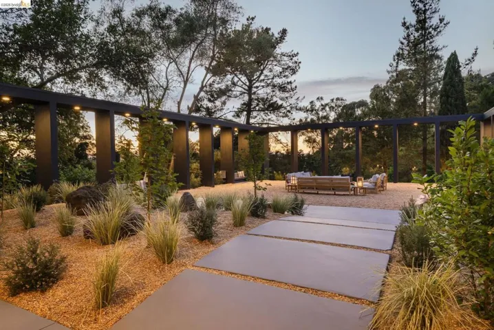 Landscaped outdoor area featuring a modern pergola structure with integrated lighting