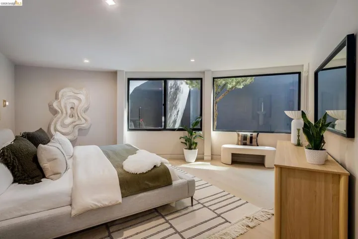 Spacious room featuring light wood-finish flooring, recessed lighting, and expansive black-framed windows
