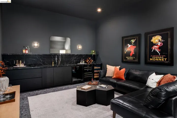 Custom bar area featuring dark cabinetry, a black marble-finish countertop and backsplash, and integrated wine refrigeration