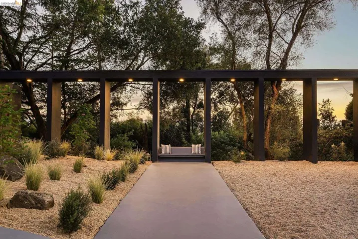 Modern outdoor trellis with recessed lighting, integrated bench seating, and a concrete pathway