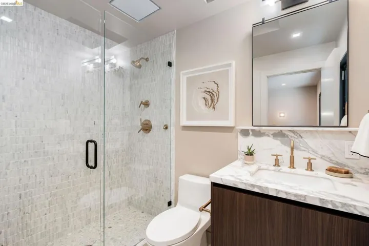 Modern bathroom featuring a glass-enclosed shower with tile surround and bronze fixtures