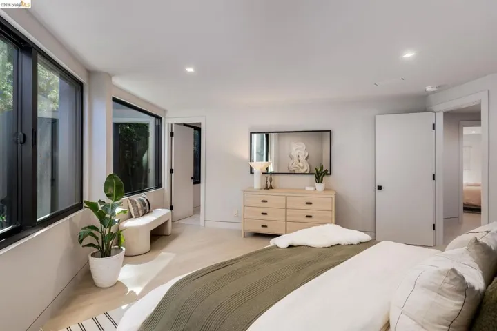 Spacious room featuring multiple large black-framed windows, light wood-finish flooring, recessed lighting, and white walls