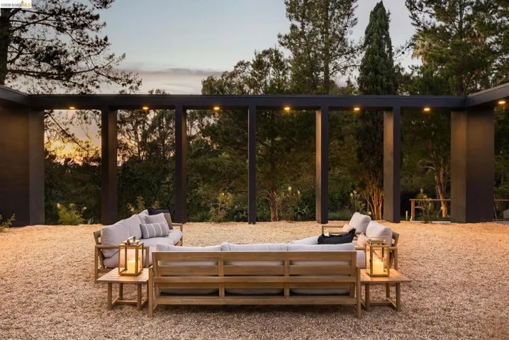 Outdoor living space featuring a dark-toned modern pergola structure with integrated downlighting