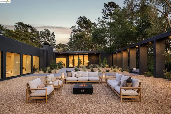 Modern exterior featuring large floor-to-ceiling windows, a gravel courtyard, and integrated exterior lighting