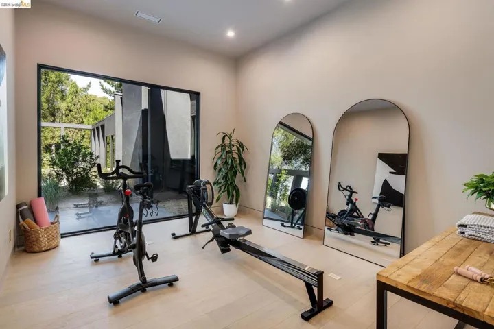 Dedicated fitness space featuring a full-height black-framed window, light wood-finish flooring, recessed lighting, and neutral wall tones