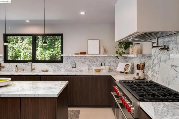 Gourmet kitchen featuring a built-in stainless steel range, marble countertops, dark wood-finish cabinetry, a pot filler, and recessed lighting