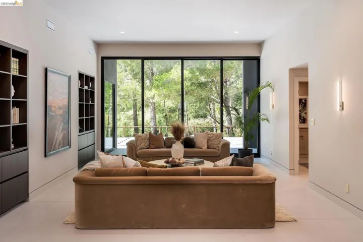 Expansive interior space featuring full-height windows, built-in shelving, recessed lighting, and wall-mounted sconces