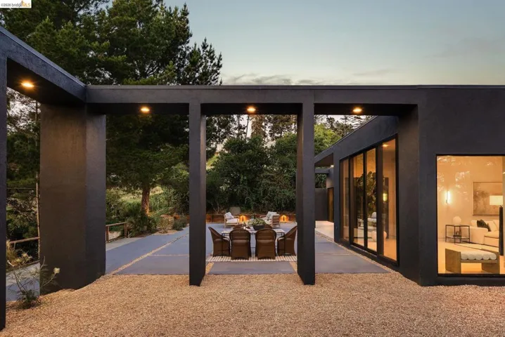 Contemporary exterior featuring dark-toned stucco, extensive glass doors, and large picture windows