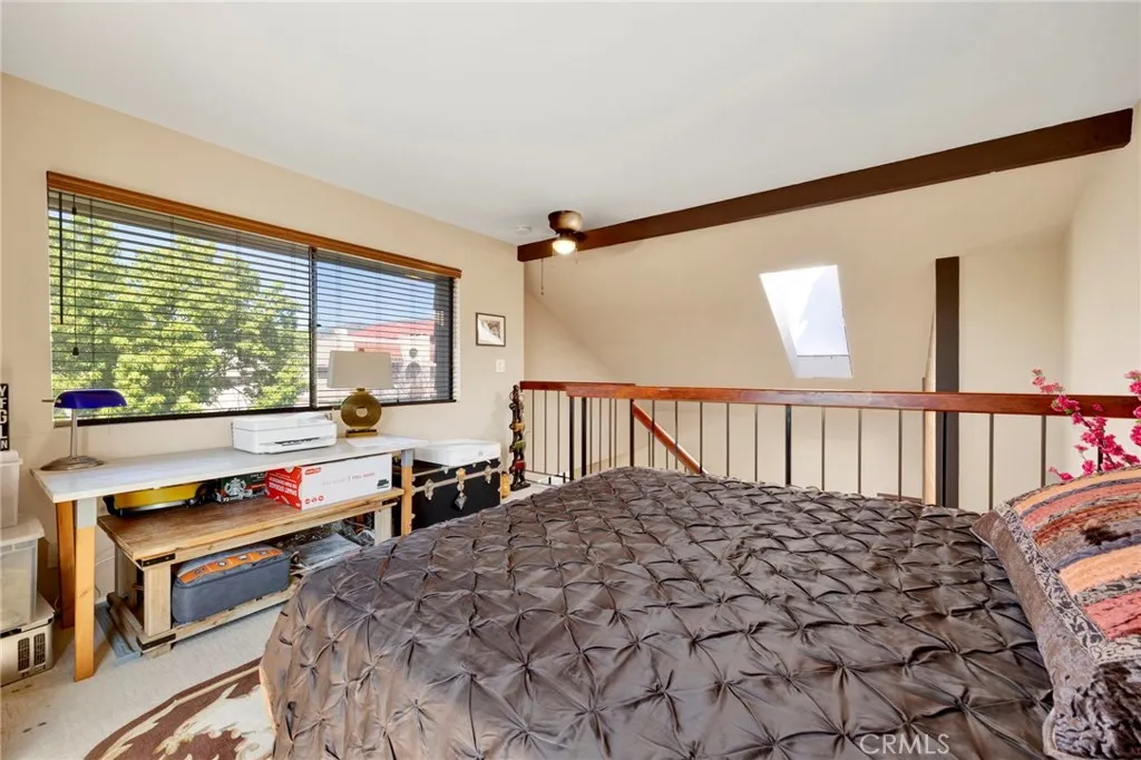 Loft bedroom area with open railing, large window, and a bright, airy feel.