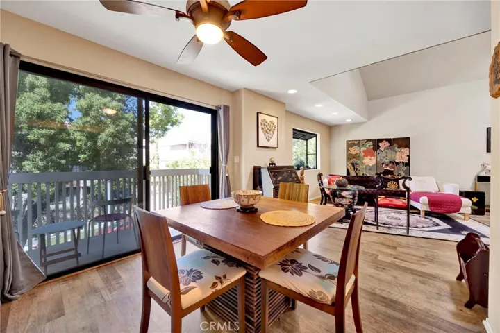 Dining area with sliding glass doors leading to a private balcony surrounded by greenery.
