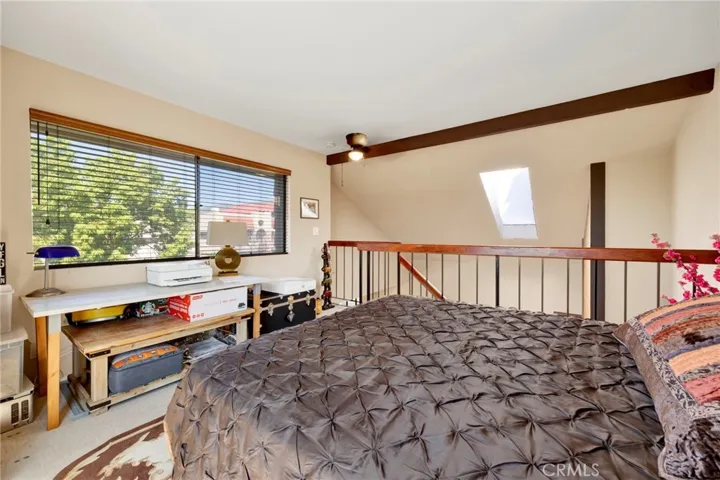 Loft bedroom area with open railing, large window, and a bright, airy feel.