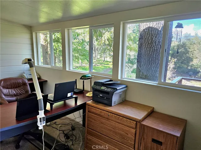 Expanded view of office, showing backyard. Part of the railing outside of the deck is showing.