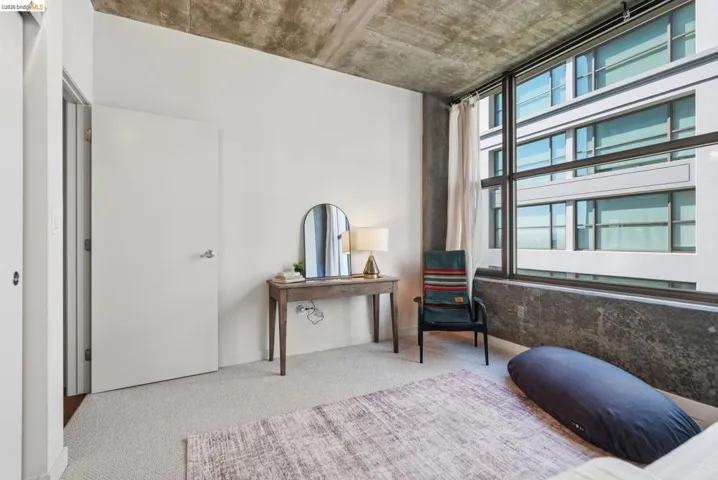 Industrial-style bedroom featuring an exposed concrete ceiling and expansive multi-pane windows