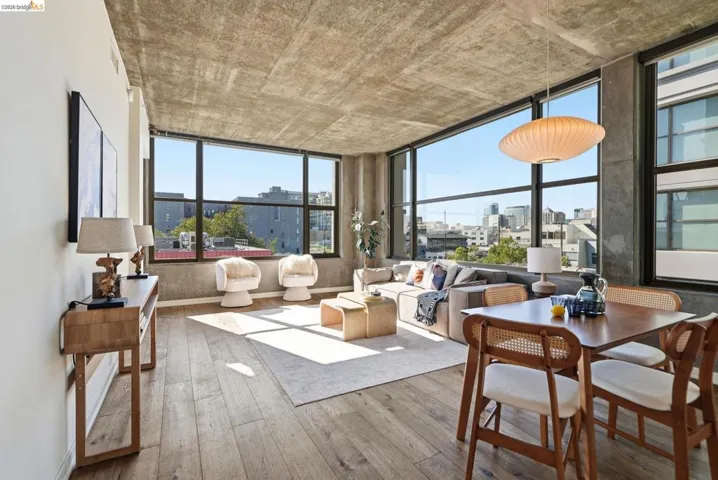 Open-concept living area with expansive wall-to-wall window panels, concrete ceilings, and wood-finish flooring