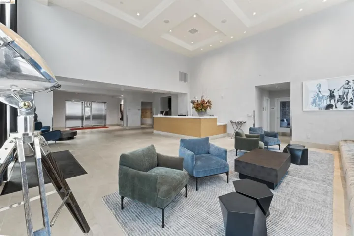 Spacious reception area featuring high ceilings with recessed lighting, an elegant coffered ceiling, light-toned floor tile, and a built-in reception desk