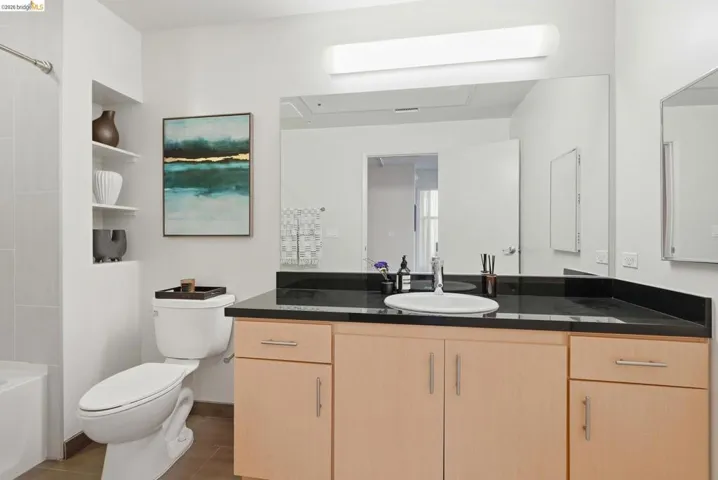Bathroom vanity featuring light wood-finish cabinetry and a black countertop