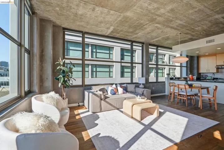 Spacious open-concept living area featuring exposed concrete ceilings and columns