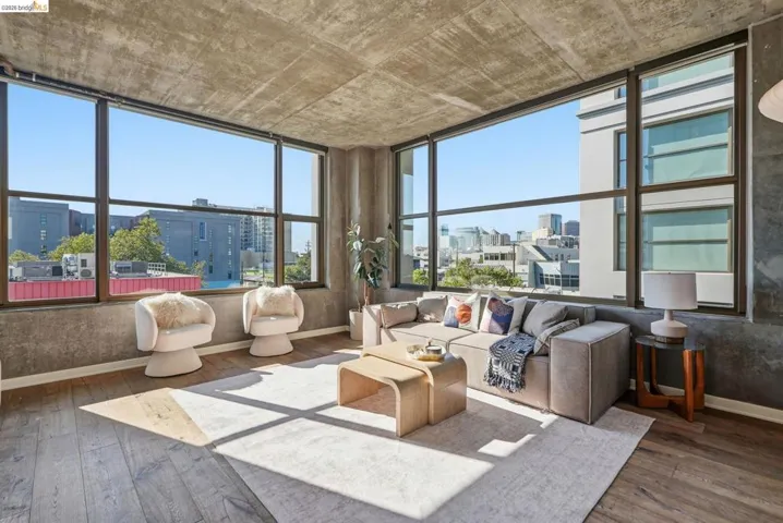 Expansive window wall with dark framing, concrete ceiling and wall finishes, wood-finish flooring, and a large area rug