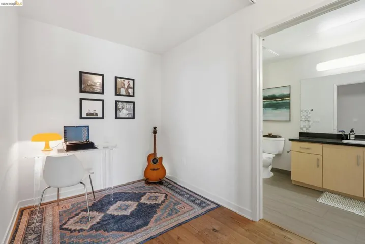 Bright room featuring wood-finish flooring and a doorway opening to a bathroom