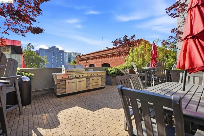 Outdoor patio featuring paver flooring, a built-in grill station with stainless steel appliances and stone facing, and a low privacy wall