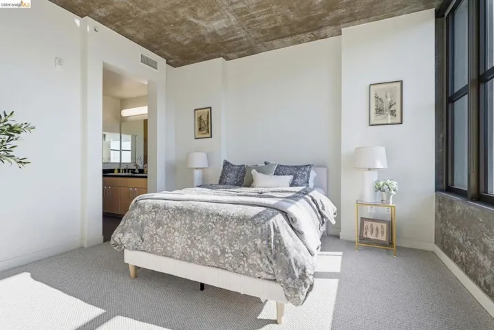 Carpeted bedroom featuring an exposed concrete ceiling and a large window with black framing
