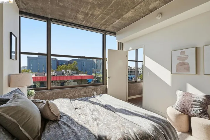 Floor-to-ceiling windows with dark framing, concrete ceiling, light-colored walls, and a white interior door
