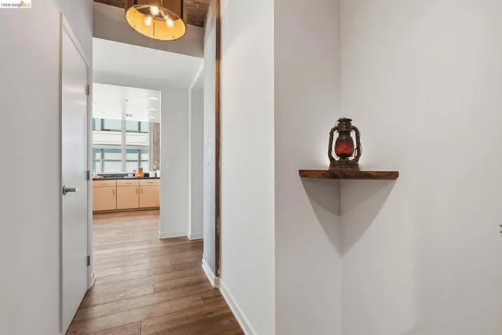 Hallway with wood-finish flooring, white walls, and a contemporary ceiling fixture