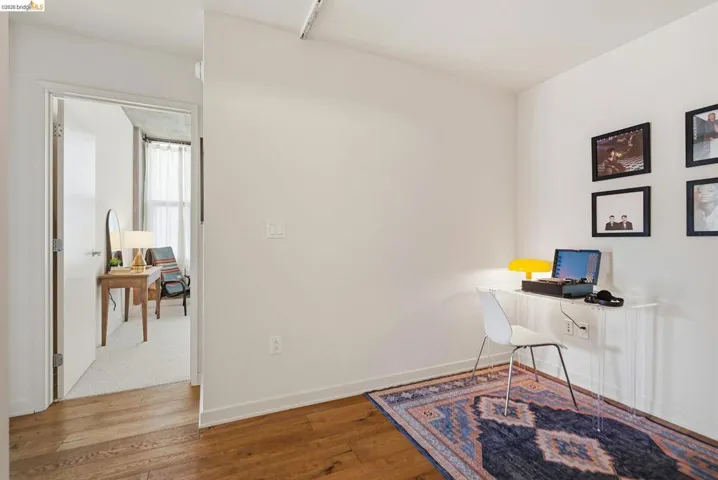 Rich wood-finish flooring extending into a spacious room with white walls