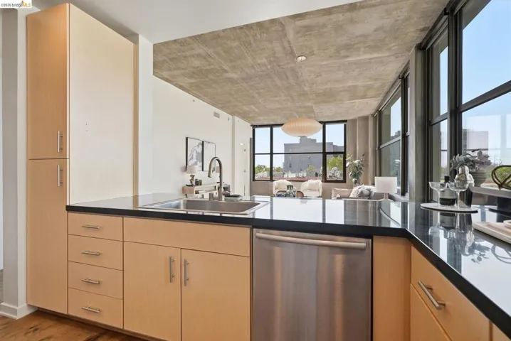 Modern kitchen featuring light wood-finish cabinetry, dark countertops, and stainless steel appliances
