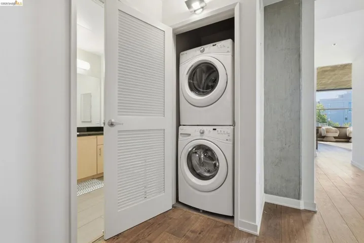 Dedicated laundry closet featuring a stacked washer and dryer, louvered bi-fold door, and overhead lighting