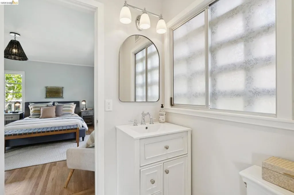 Bathroom vanity with a chrome faucet, white sink, and white cabinetry featuring chrome hardware