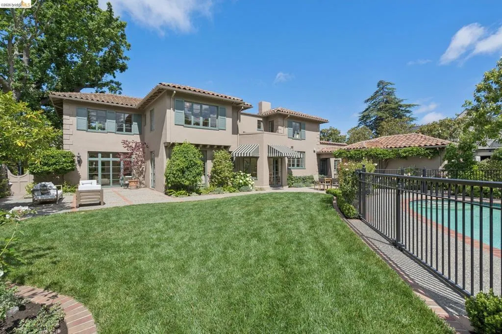 Mediterranean-style exterior featuring a stucco finish, terracotta roof tiles, and decorative window shutters