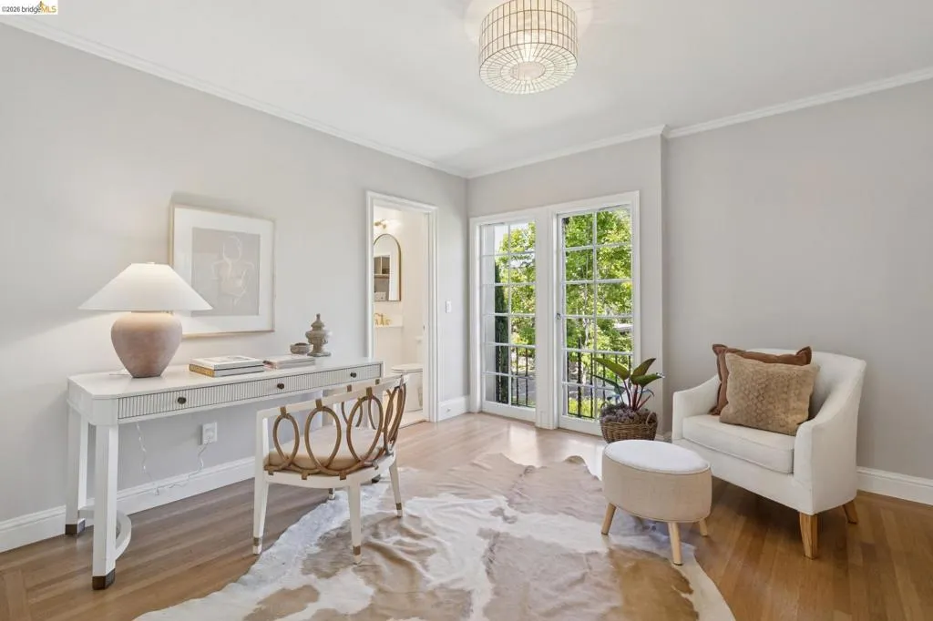 Light-filled interior space featuring wood-finish flooring, white crown molding, and a contemporary flush-mount ceiling fixture