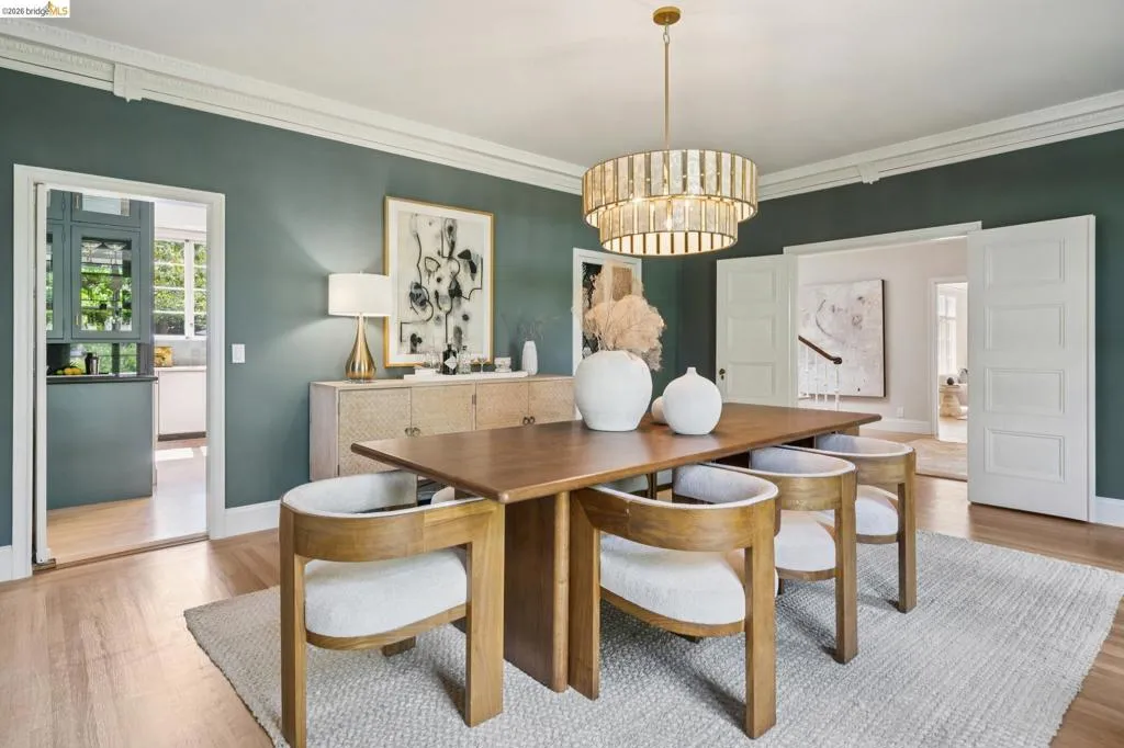 Formal dining space featuring rich wall color, light wood-finish flooring, and a tiered chandelier