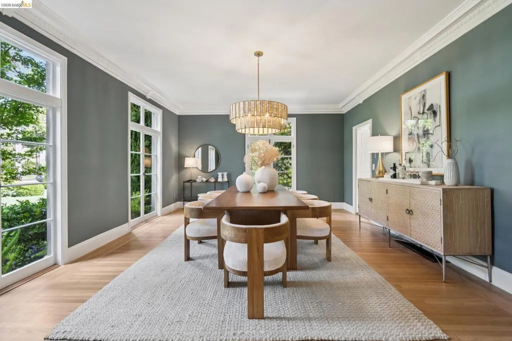 Dining area featuring wood-finish flooring, white crown molding, and a tiered chandelier