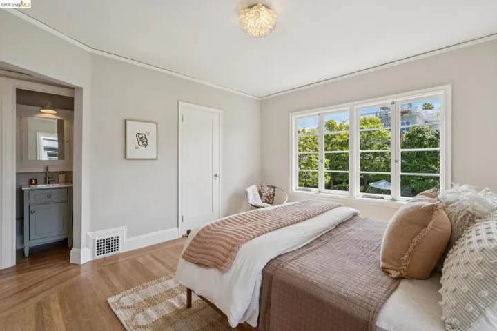 Bedroom with en-suite split bath, featuring light-colored walls and wood-finish flooring. Cedar lined closet.