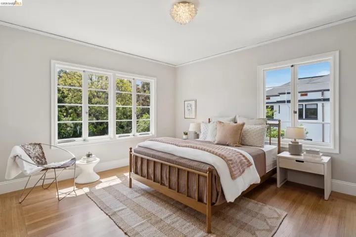 Light-filled room featuring wood-finish flooring, two large windows with white trim, a built-in ceiling light fixture, and crown molding